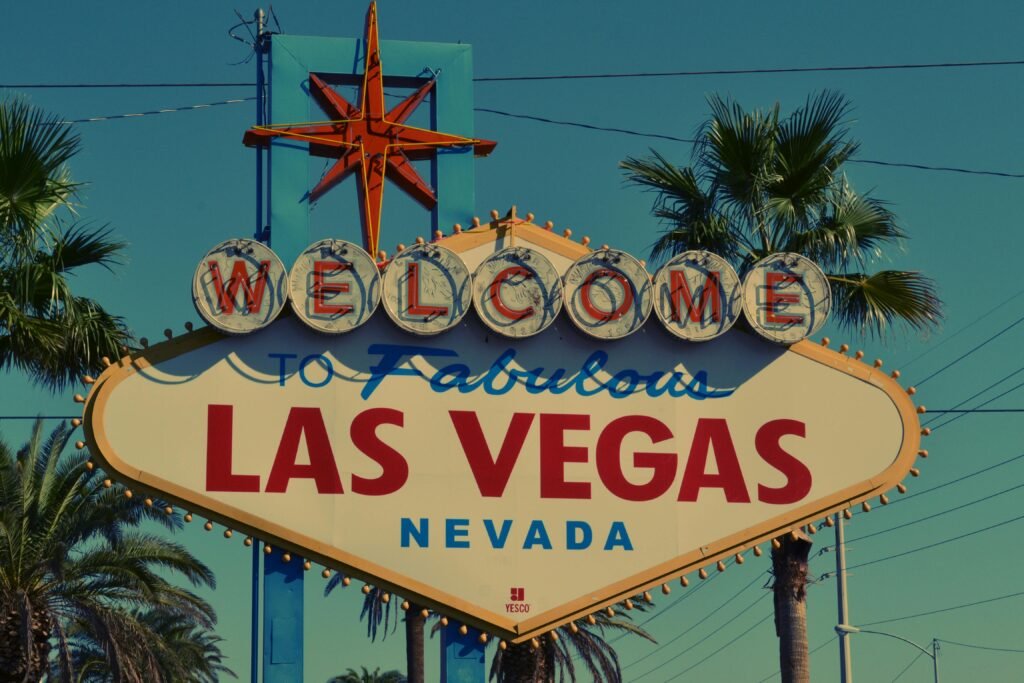 The famous Welcome to Las Vegas sign framed by palm trees under clear skies.